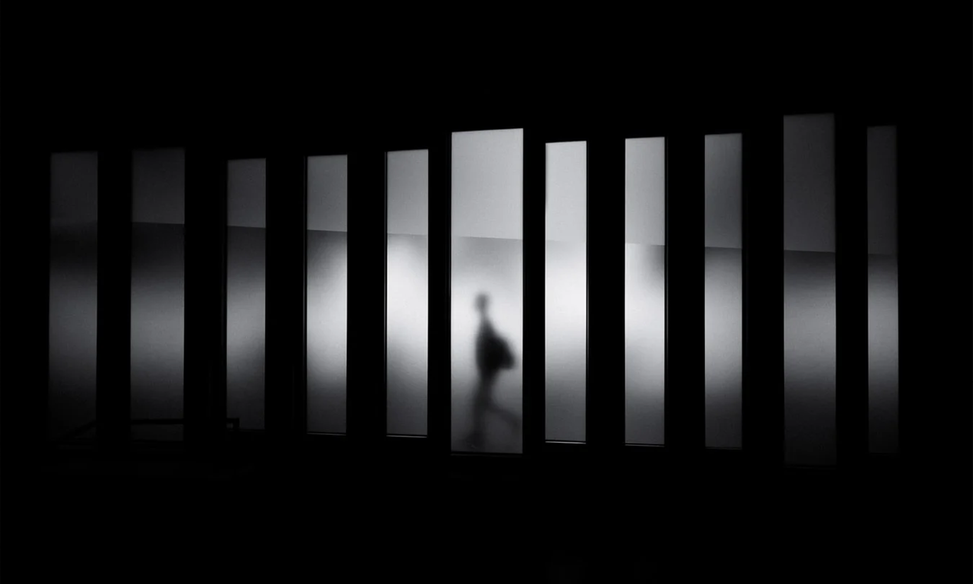 Pessoa andando ao lado de uma parede com janelas de vidro.