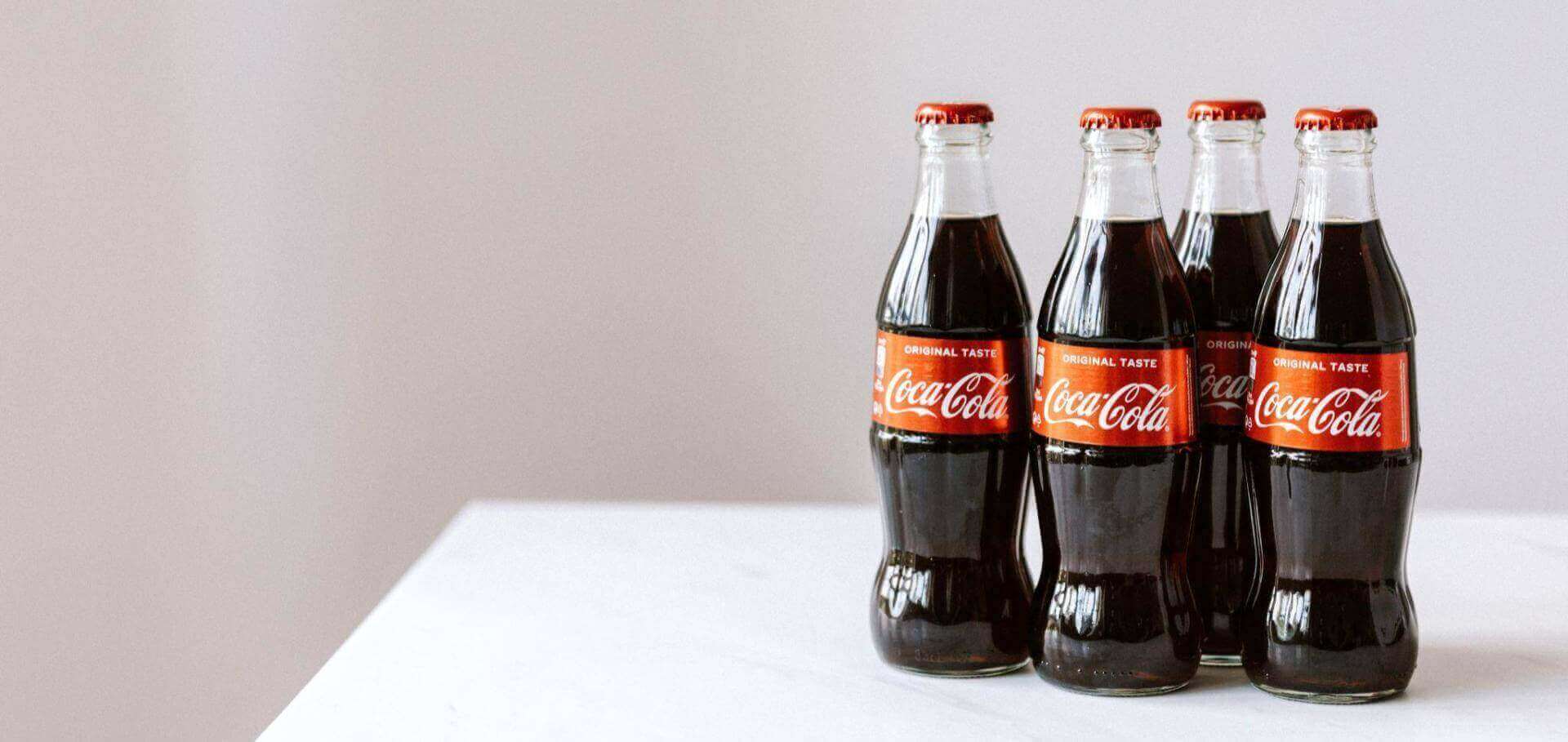 Quatro garrafas de vidro da Coca-Cola.